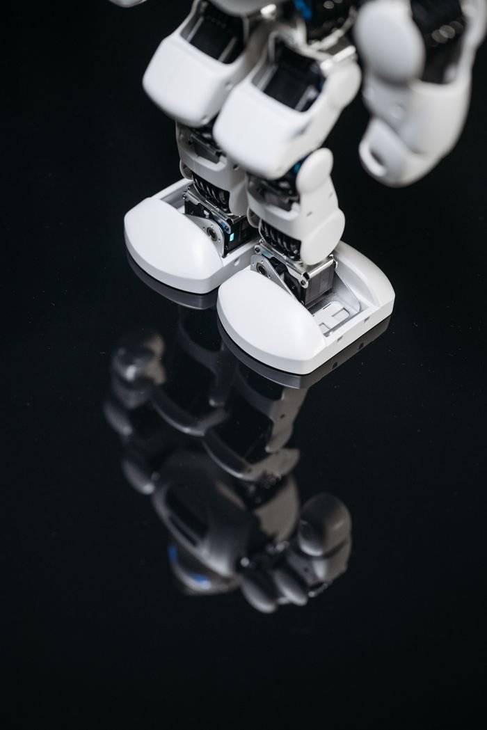 About High-tech robot feet reflecting on a glossy surface, showcasing futuristic design.