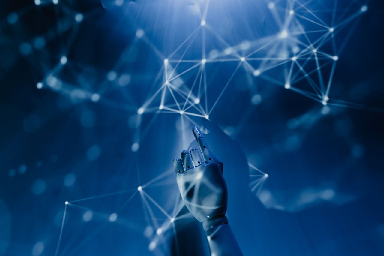 Home A robotic hand reaching into a digital network on a blue background, symbolizing AI technology.
