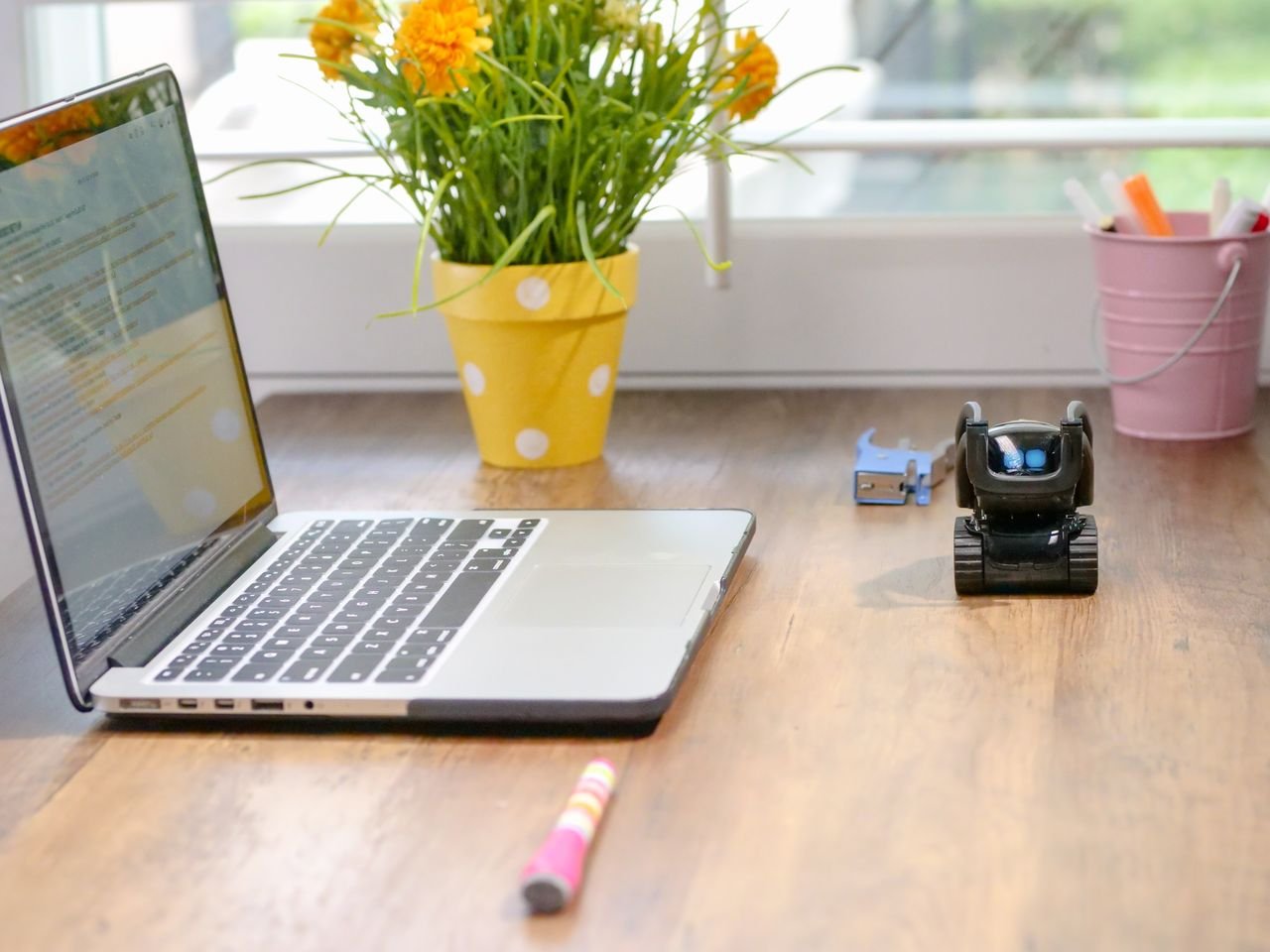 Mastering the First Impression: Your intriguing post title goes here Stylish workspace featuring a laptop, toy robot, and vibrant flowers in natural light.